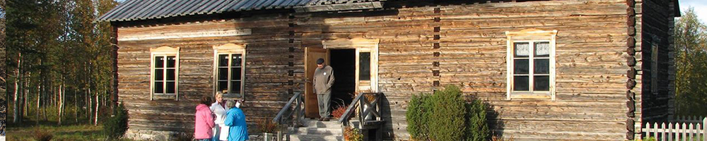 Visitors at an old wooden building in Hetta amid autumn foliage