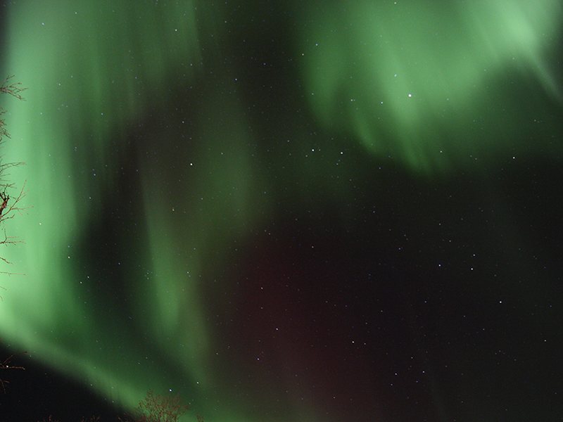 A sweeping green aurora borealis filling the night sky over Finnish Lapland