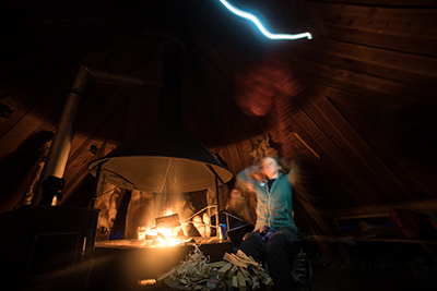 Inside a traditional kota at night with a fire burning at the centre