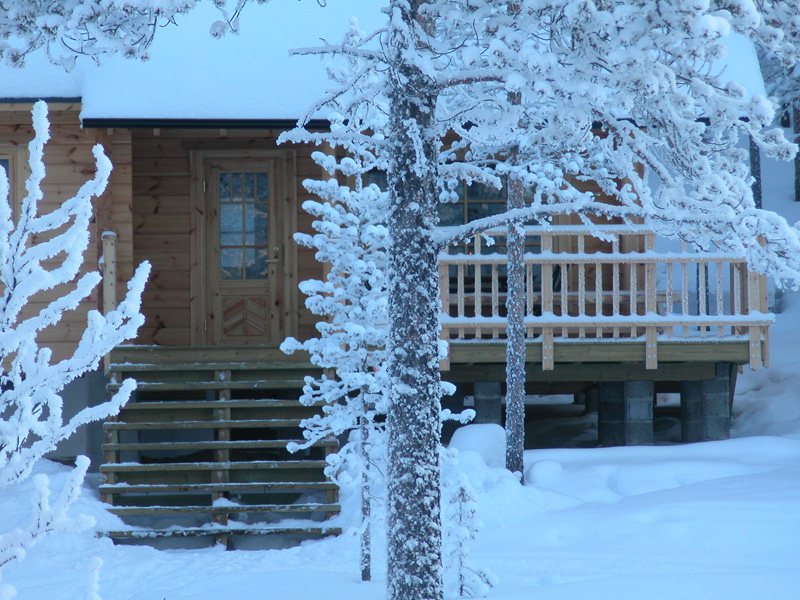 A snow-covered timber wilderness cabin among frosted trees in deep winter